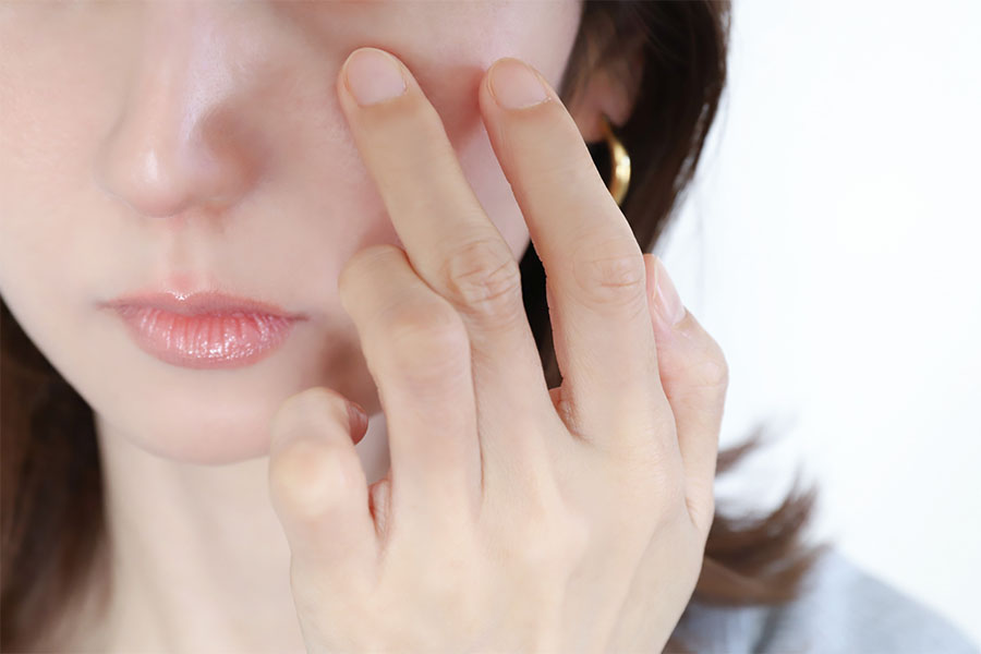 顔を触る女性の画像